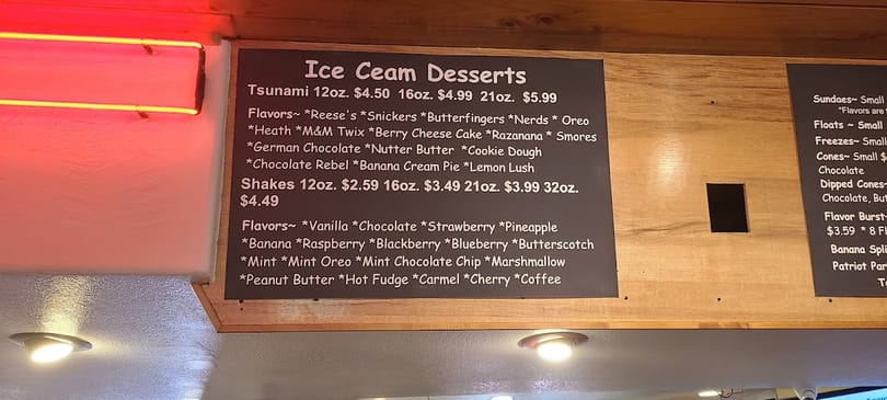 Ice cream and shake menu board with prices and many flavor options in a restaurant.